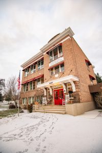 a brick school building with red doors that is now a bed and breakfast