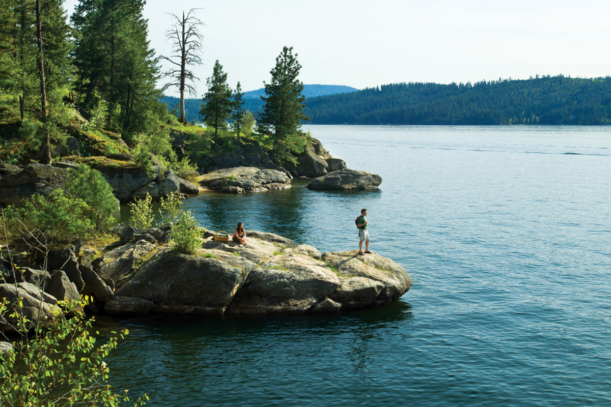 people stand on a lakeside rock in Coeur d'Alene