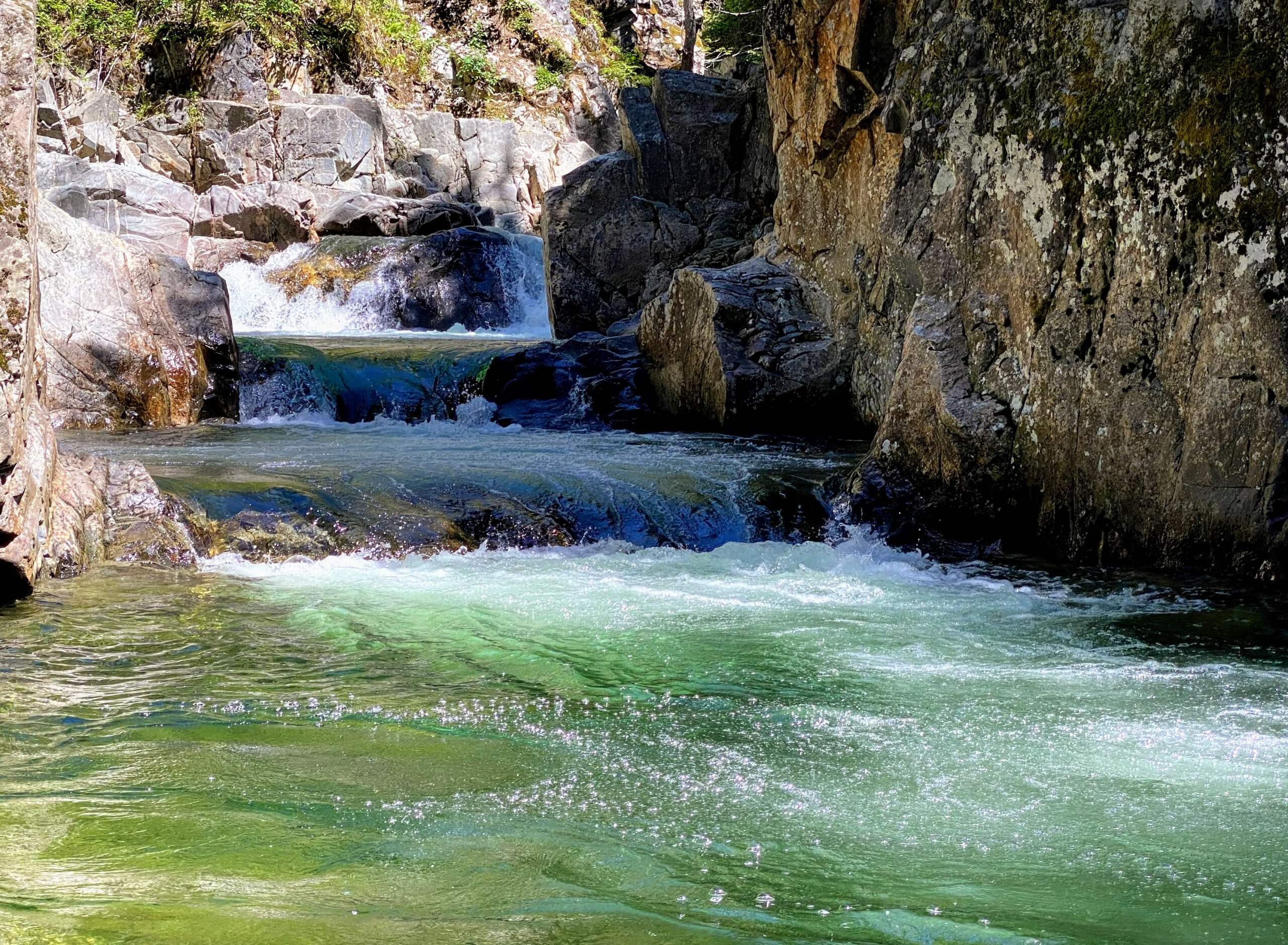 The Grouse Creek Falls ripple, bubble, and shimmer in sea-green hues, dipping down steps across different rock elevations.