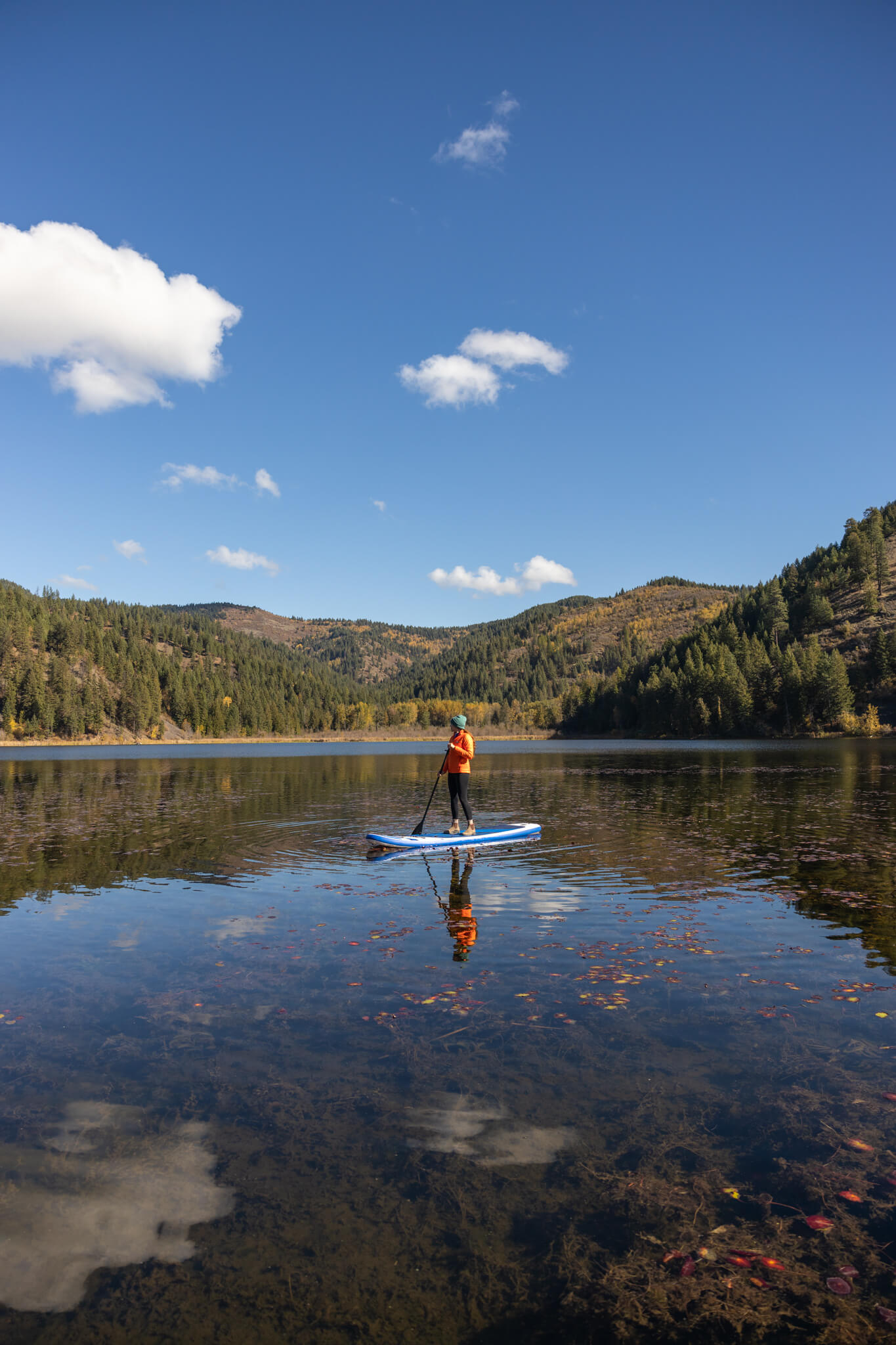 A person paddleboarding on Fremont Lake surrounded by tree-covered mountains.