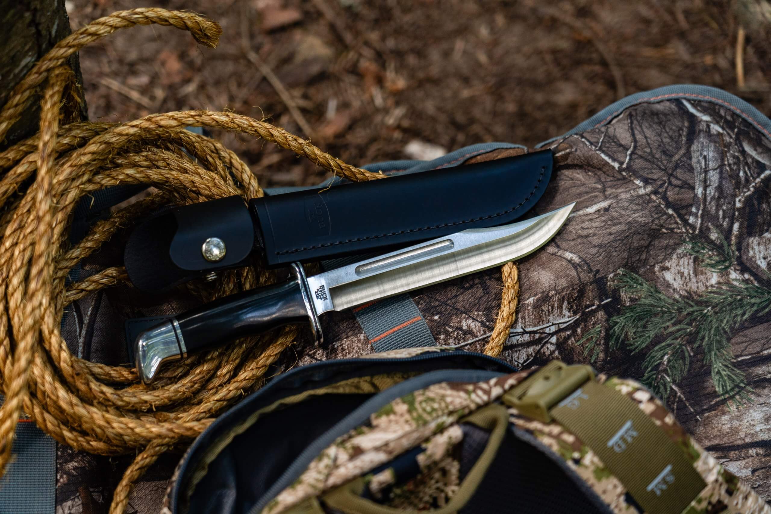 An upclose, overhead view of a Buck Knives knife and its leather carrying case on top of a coiled rope.