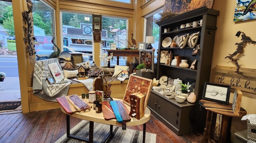 Various tables and shelves holding cups, bowls, pillows and other types of home decor inside Driftwood Mercantile.