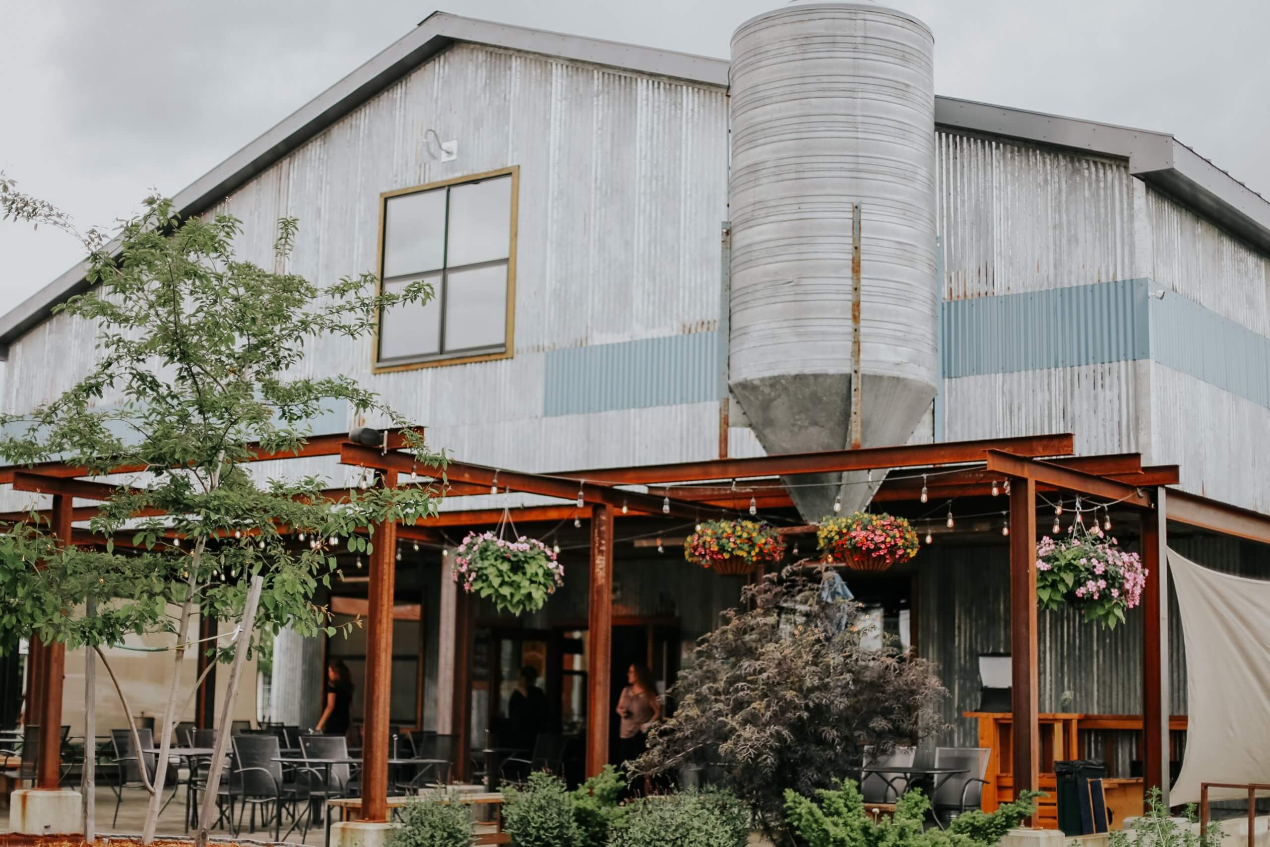 An outside view of the Matchwood Brewery building and the patio, trees and plants out front.