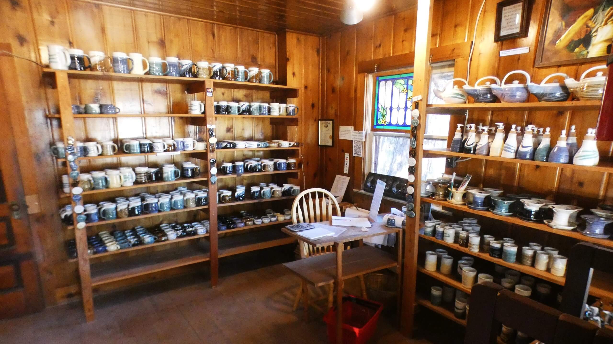 Several shelves with pieces of pottery on display inside the Sondahl Pottery shop.