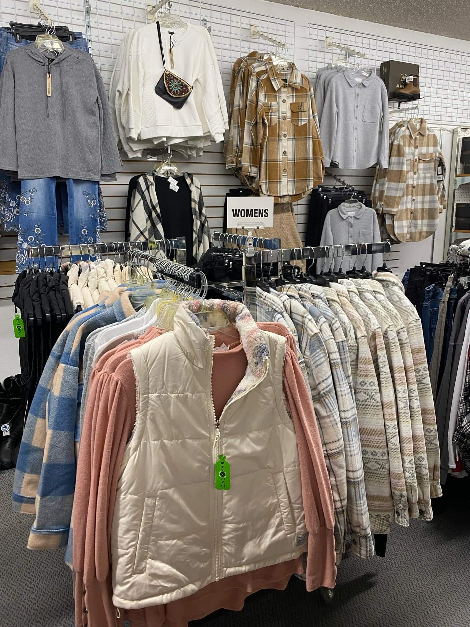 Several jackets, shirts, vests and jeans displayed on racks inside the Country Fair in St. Maries shop.