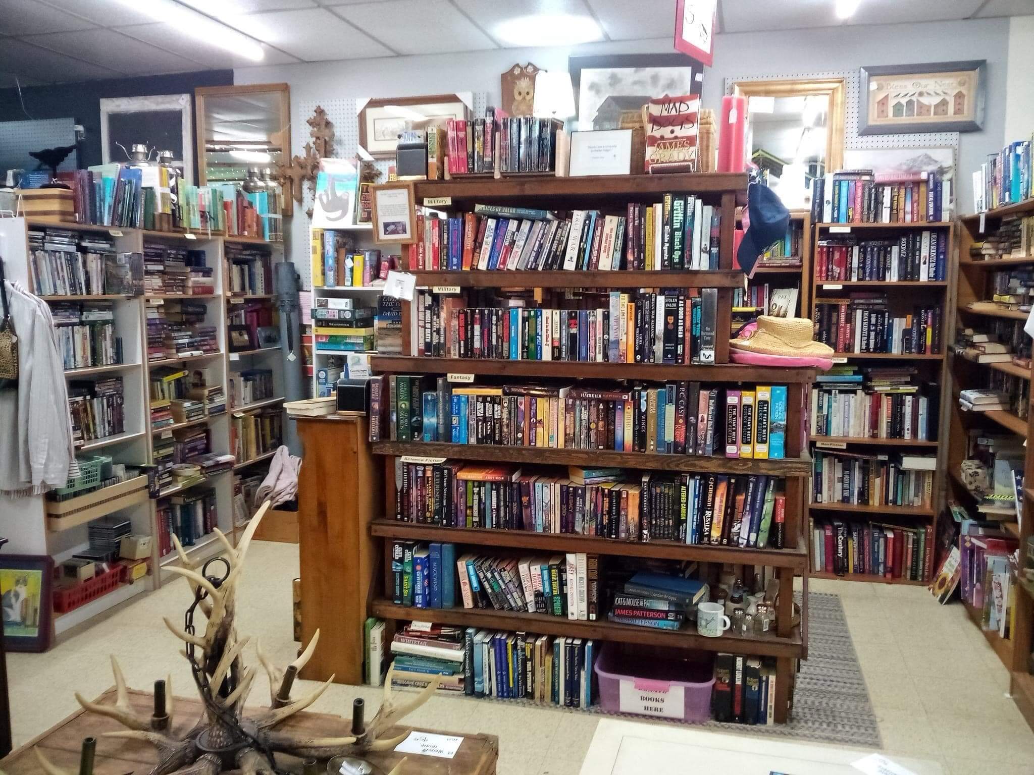 Several rows of bookcases filled with books and paintings on the walls inside Happy's Marketplace.