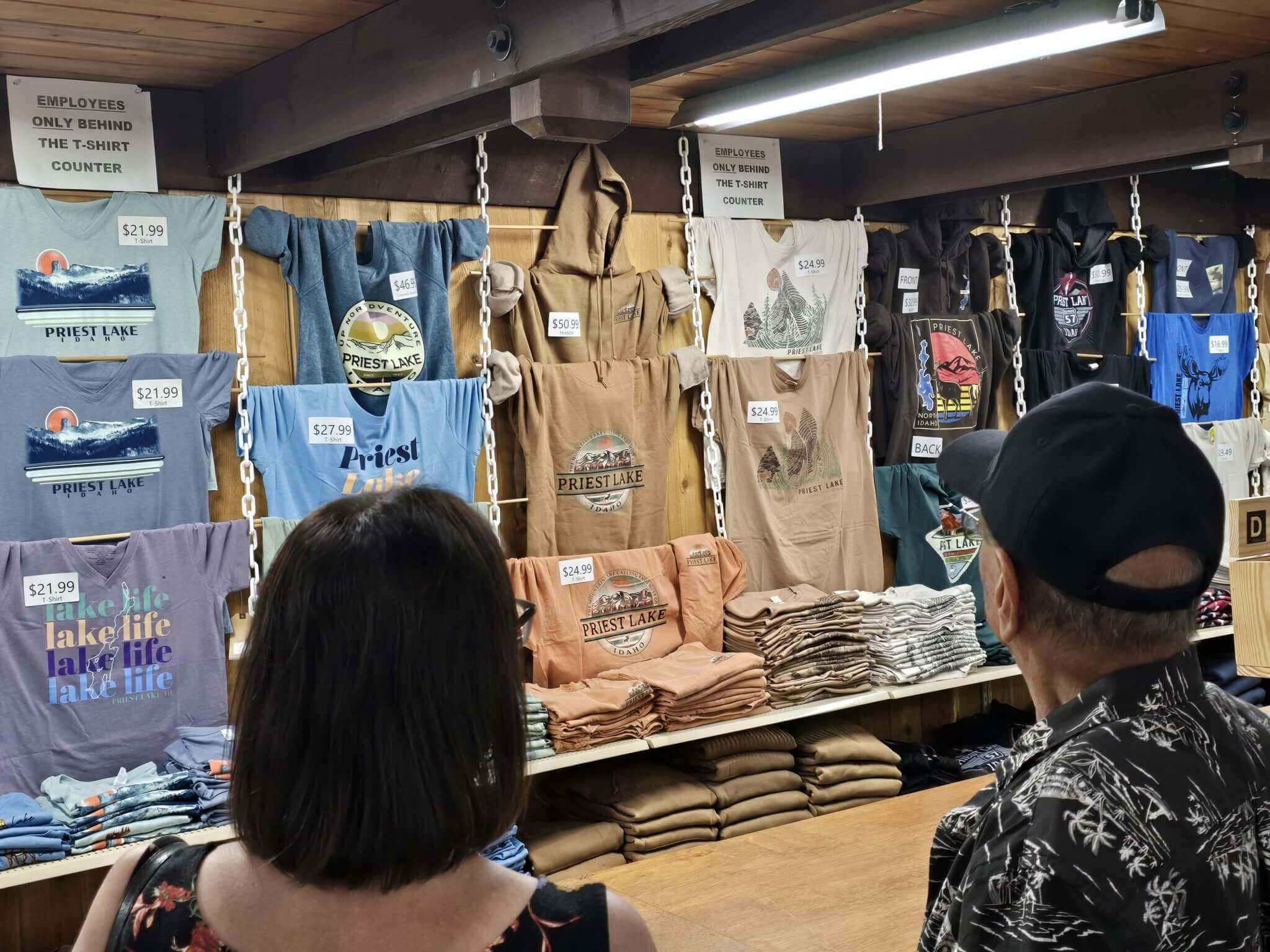 alt="Two people looking at several shirts on display inside The Tamrak store."