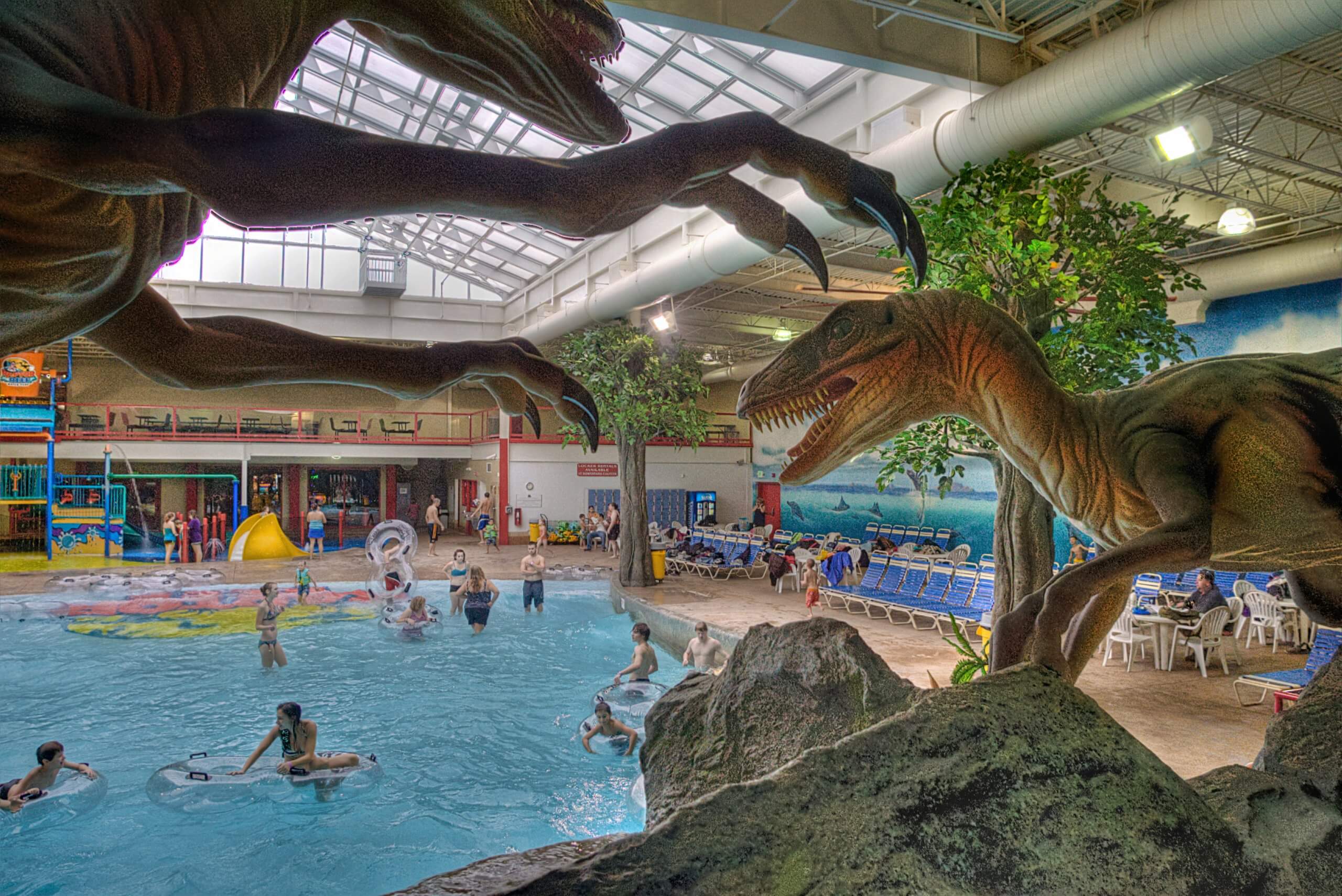 Indoor water slides at Triple Play Resort Hotel & Suites with people enjoying the water and dinosaur sculptures around the area.