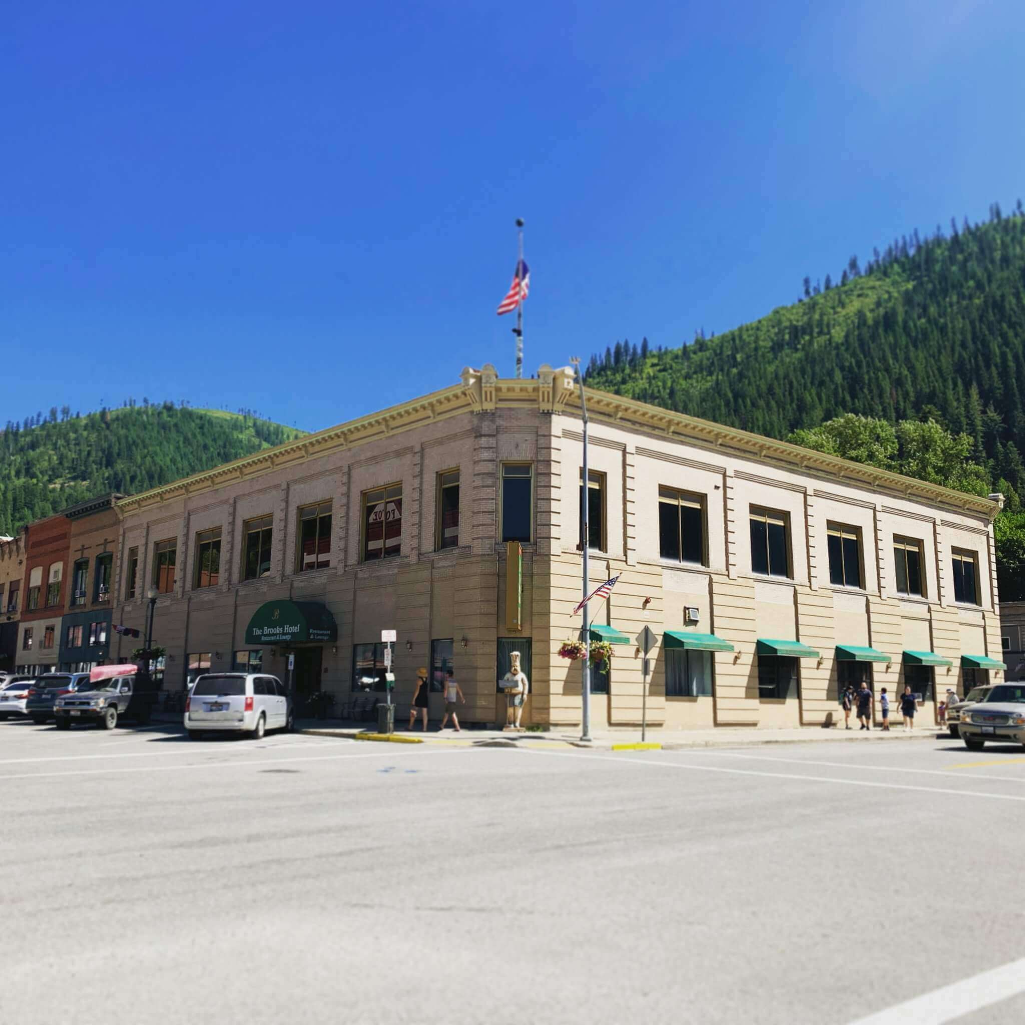 Exterior view of the Brooks Hotel in summer, surrounded by green trees and a clear blue sky.