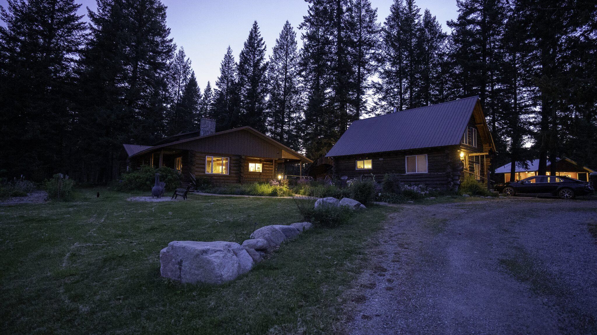 Cedar Mountain Farm log cabins illuminated at night, nestled among tall trees with a starry sky above.