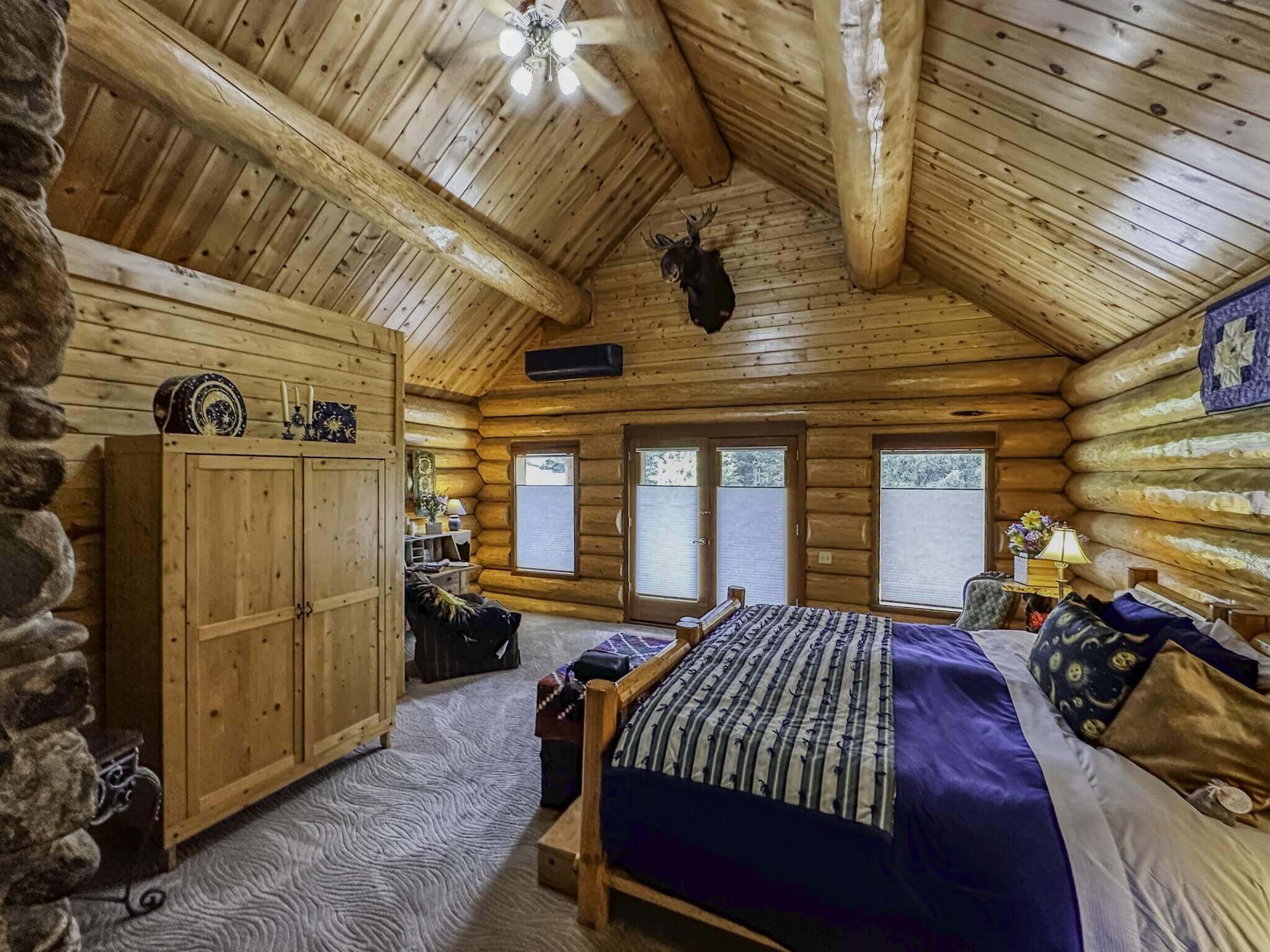 Cozy log cabin room at Log Spirit Bed & Breakfast, featuring a wooden bed, rustic furniture, and large windows.