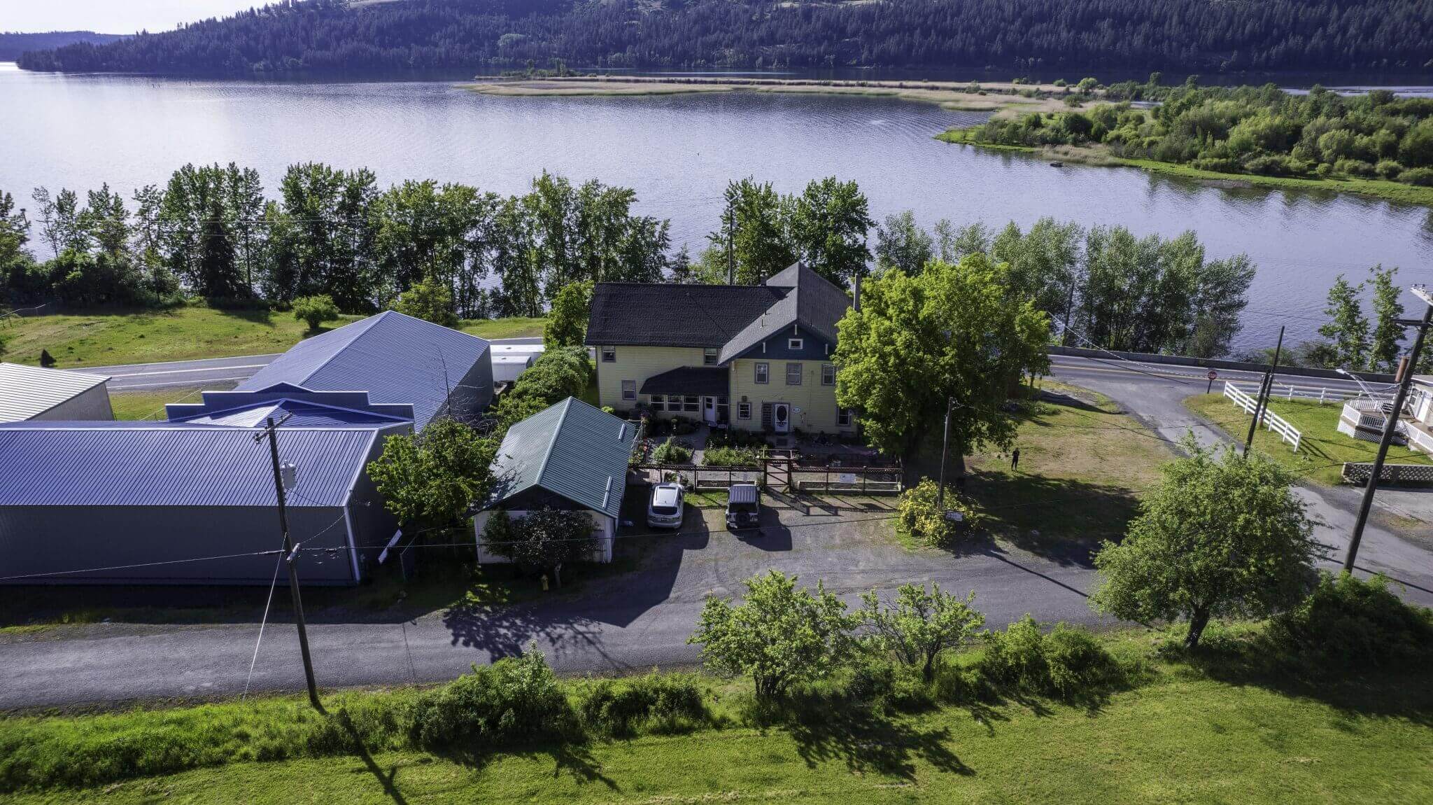 Aerial view of Osprey Inn near the water, surrounded by trees and a grassy landscape.