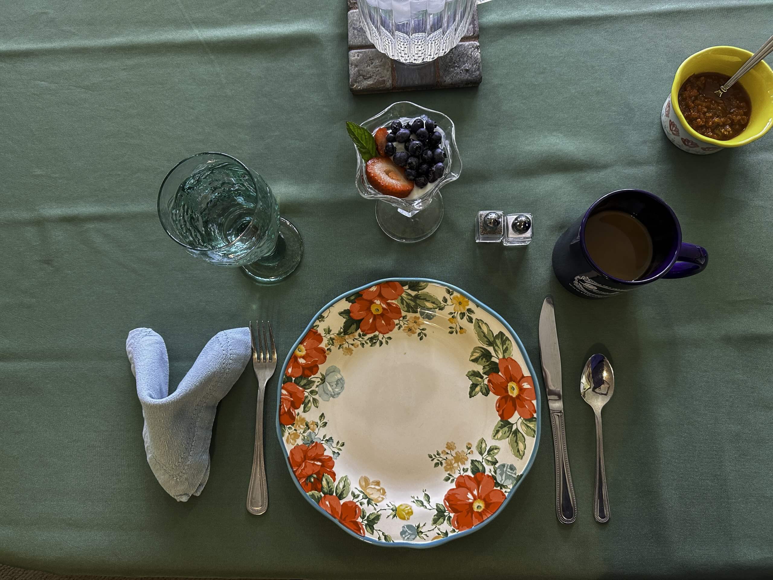 A colorful breakfast setting at Osprey Inn, featuring a floral plate, fresh fruit, coffee, and oatmeal.