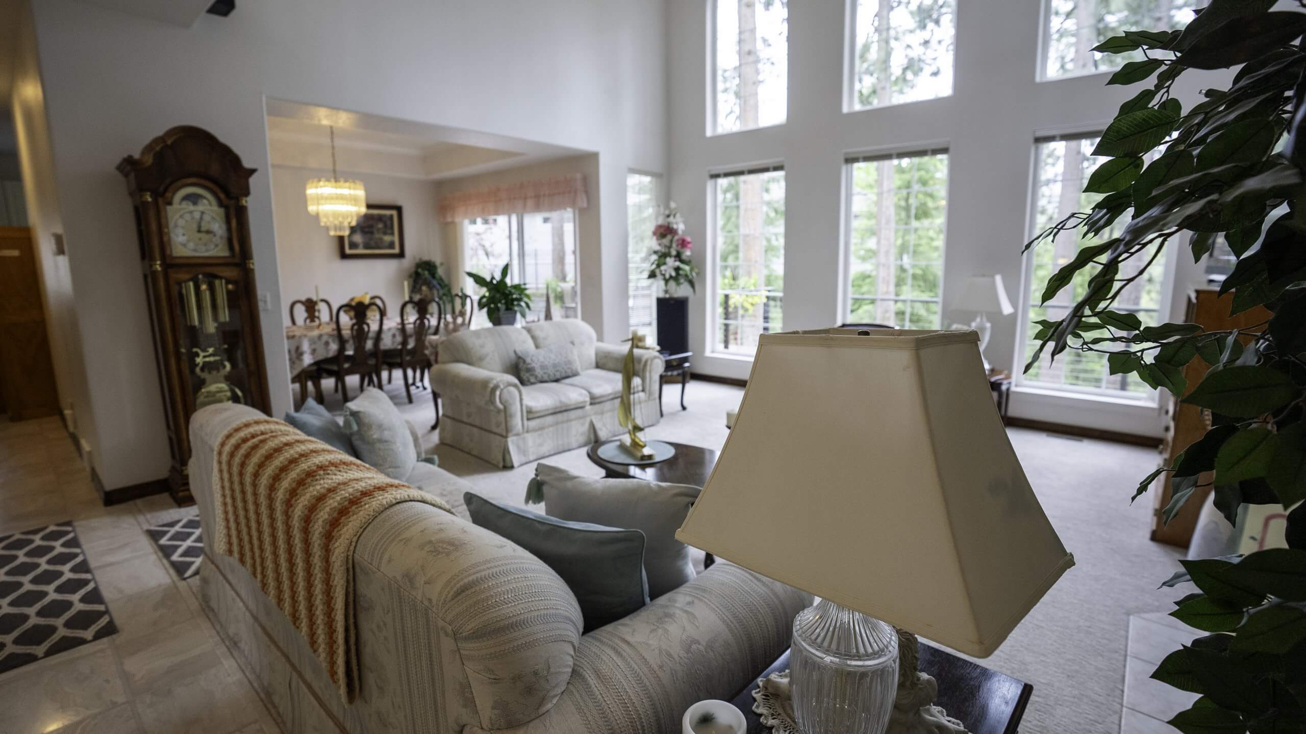 The cozy living room at River Cove Bed & Breakfast, featuring elegant furniture, large windows with natural light, and a view into the dining area.